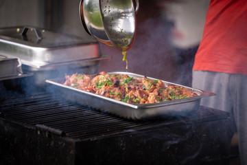 A man bakes meat on a grill and sprinkles with spices