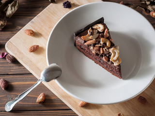 Sweet chocolate cake topping with chocolate and almond nut decorate with dried flower on wooden background