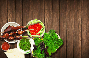 Juicy meat kebab of lamb and beef with fresh herbs lie on a wooden table