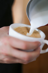 cup of coffee in hands of man on a background, barista preparing cappuccino