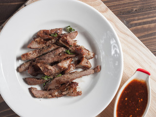 Charcoal-boiled pork neck and sauce on a wooden floor .Grilled Pork thailand style