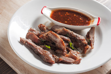Charcoal-boiled pork neck and sauce on a wooden floor .Grilled Pork thailand style