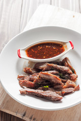 Charcoal-boiled pork neck and sauce on a wooden floor .Grilled Pork thailand style