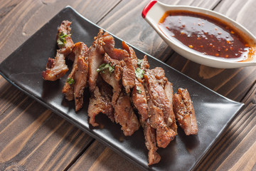 Charcoal-boiled pork neck and sauce on a wooden floor .Grilled Pork thailand style
