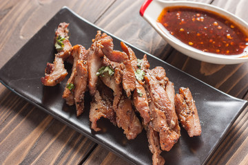 Charcoal-boiled pork neck and sauce on a wooden floor .Grilled Pork thailand style