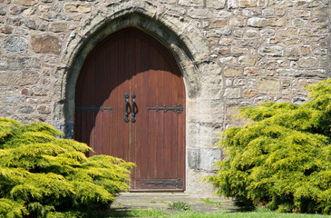 Fototapeta na wymiar wooden church doors in stone arch and stone walss