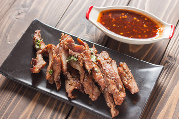 Charcoal-boiled pork neck and sauce on a wooden floor .Grilled Pork thailand style