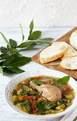 Vegetable soup with chicken with bay leaf in a white plate on a light background.  laurel as an aromatic spice in a dish. Soft focus. Place for text. Copy Space
