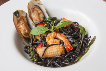 Black spaghetti with spicy seafood on wood table