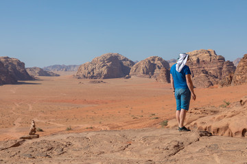 A tourist standing by the look out of a panoramic view of the desert in Wadi Rum, Jordan, Middle East.