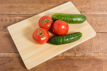 Tomatoes and cucumbers on a wooden background.