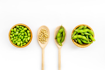vegan food with green soybeans or edamame in spoon and bowl on white background top view