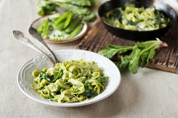 green fettuccine pasta with spinach leaves and green peas. ready meals, vegetarian cuisine. Italian food. square format