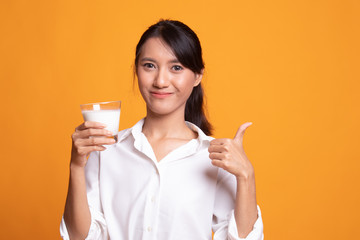 Healthy Asian woman drinking a glass of milk thumbs up.