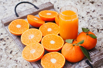 Fresh orange juice in clear glass. Sliced citrus on wooden table.