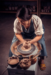 Charming artisan girl sculptor works with clay on a Potter's wheel and at the table with the tools. Handicraft industry.