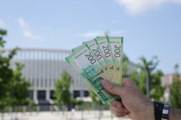 Male hand holds a new Russian banknote two hundred rubles on the background of a building and blue...
