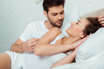 Fototapeta na wymiar handsome man looking at girl smiling while lying on bed