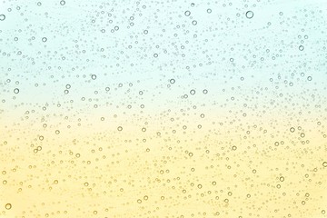 In selective focus of many droplets on a glass window with yellow green background 