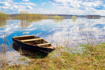 Old wooden boat near the river. Spring flood
