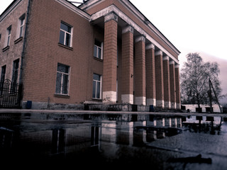 Fototapeta na wymiar Old brown building with columns. A building with columns is reflected on the wet ground