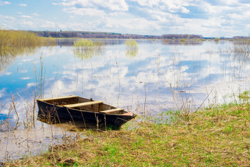 Naklejka premium Old wooden boat near the river. Spring flood