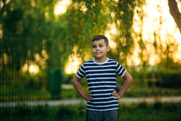 Fototapeta premium A little boy in a striped T-shirt standing in front of green background. Smiling and looking to the photographer
