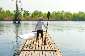 Man carrying kayak and oar after water sports at warm weather © serguastock