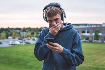 Upset teenager listening to music with his headphones on an overcast day.