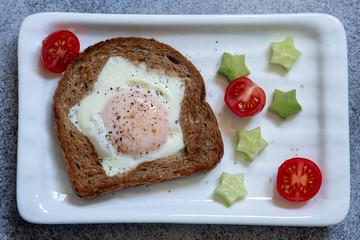 Egg fried in a hole star-shaped toast with avocado and tomato