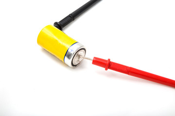 Multimeter wires and yellow battery. Checking battery voltage. Red to plus. Close up, isolated on...