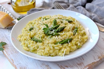 Italian risotto with spring asparagus and parmesan cheese in plate on light background. Top view...