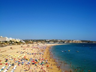 View from the cliffs to the people, tourists on the sandy beach Praia da Rocha at Portimao. Algarve beach during the summer vacation, Portugal, Europe.