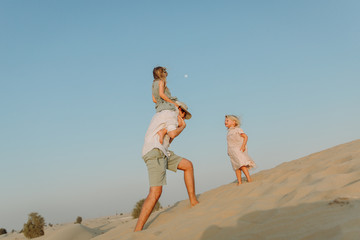 Young father having fun with his daughters in the desert