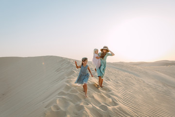 Young beautiful mother with two little daughters in the desert in Dubai