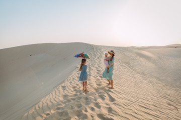 Young beautiful mother with two daughters walking in the desert