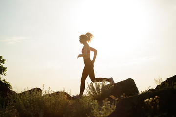 Young Beautiful Woman Running on the Mountain Trail at Hot Summer Sunset. Sport and Active Lifestyle.