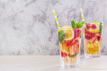 Glasses of Spring Alcoholic Beverage Side View. Ripe Strawberries and Raspberries, Orange, Lemon and Green Mint Leaves Mixed Rum. Two Portion of Homemade Drink with Striped Tubule for Relax Time