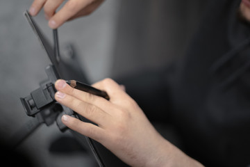 Close-up of young man painting with pencil on easel