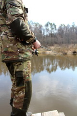 Angler in camouflage clothing, fishing on spinning