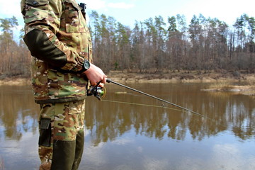 Fisherman in camouflage clothing, fishing on spinning.