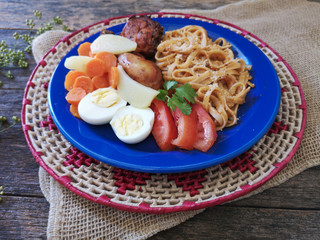Food dish with spaghetti pasta, roasted chicken and salad on wooden background