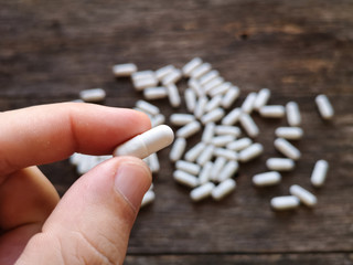 Hand holding capsules pills white on wooden background. Medical supplies. Natural supplements and...