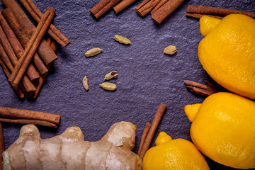 lemon, ginger, cinnamon and spices on a background of black stone