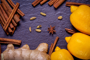 lemon, ginger, cinnamon and spices on a background of black stone