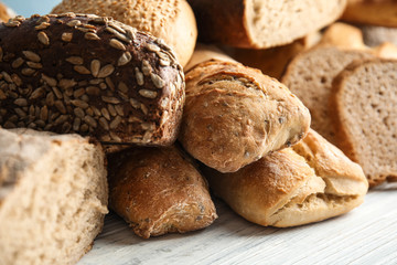 Different kinds of fresh bread on wooden table, closeup