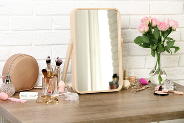 Different makeup products and accessories on dressing table in room interior