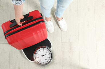Woman weighing suitcase indoors, top view. Space for text