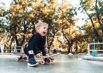 Young kid sitting in the park on a skateboard. © teksomolika