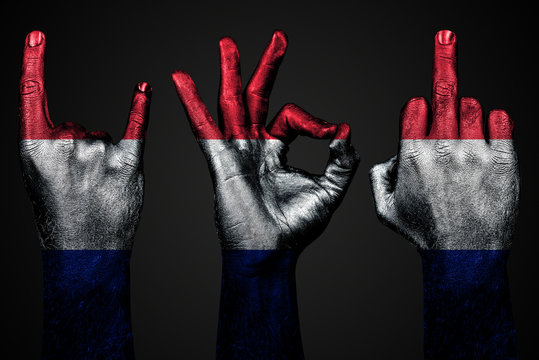 a set of three hands with a painted flag France show middle finger, goat and Okay, a sign of aggression, protest and approval on a dark background.
